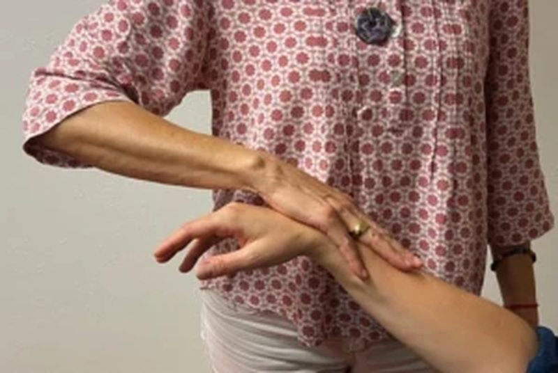 Eine Hand liegt prüfend auf dem ausgestreckten Arm einer Person, ein kinesiologischer Muskeltest.